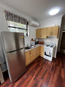 eine Küche mit einem Kühlschrank aus Edelstahl und Holzböden in der Unterkunft 2 bedroom retreat with Swimming Pool in Baulkham Hills