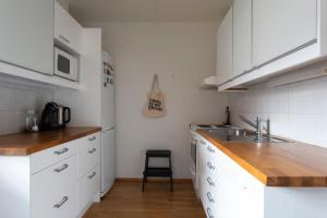 a kitchen with white cabinets and a wooden counter top at 2ndhomes Katajanokka Apartment with Seaview and Sauna in Helsinki