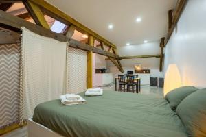 een slaapkamer met een groen bed en handdoeken bij The Backstage in La-Roche-en-Ardenne