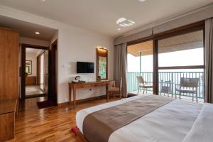1 dormitorio con cama, escritorio y balcón en StayVista at Paradise Valley View with Terrace Access en Munnar