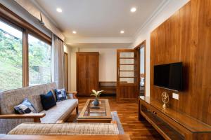ein Wohnzimmer mit einem Sofa und einem TV in der Unterkunft StayVista at Paradise Valley View with Terrace Access in Munnar