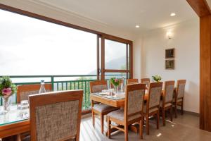ein Esszimmer mit einem Tisch und Stühlen sowie einem Balkon in der Unterkunft StayVista at Paradise Valley View with Terrace Access in Munnar