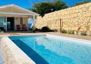 a swimming pool in front of a stone wall at Villa Daniela in Punta Rucia