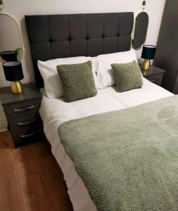 een slaapkamer met een groot bed met groene en witte kussens bij Impeccable 2-Bed House in Londen