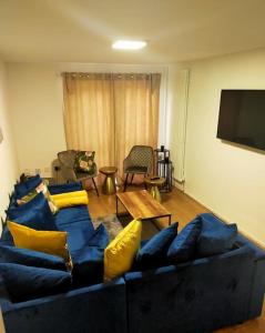 a living room with a blue couch with yellow pillows at Impeccable 2-Bed House in London