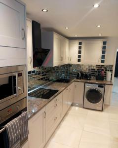a large kitchen with white cabinets and a dishwasher at Impeccable 2-Bed House in London