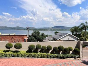 a wall with a row of trees and bushes at The Windsor- Hartbeespoort Dam in Hartbeespoort