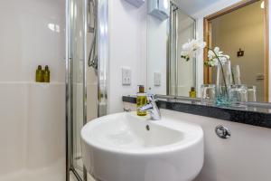 a white bathroom with a sink and a shower at KM Apartments in Edinburgh