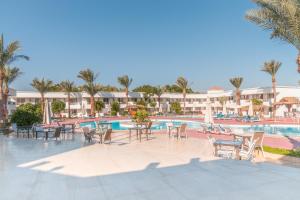 a resort pool with tables and chairs and palm trees at Viva Sharm in Sharm El Sheikh