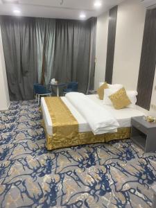 a bedroom with a bed and two blue chairs at Orchida Turaif Hotel 1 in Ţurayf