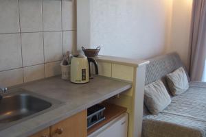 a small kitchen with a sink next to a bed at Patio Apartamenty i Pokoje in Niechorze