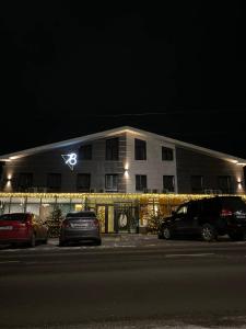 a building with christmas lights and cars parked in front of it at Hotel 78 Cafe in Karakol