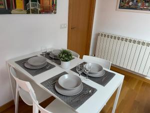 una mesa blanca con sillas, platos y copas de vino en Vivienda turística Los Tejados, en Soria