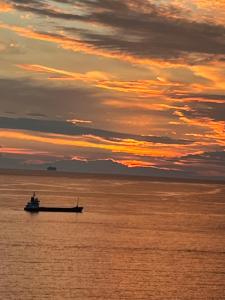 a boat in the ocean with a sunset at Bluemoon Suites Sarande in Sarandë