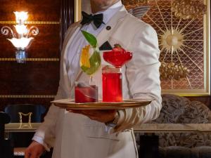 a man holding a tray with two cocktails on it at The Ritz London in London
