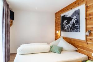 um quarto com uma cama branca e uma parede de madeira em Apart-hochzillertal Gartenwohnung em Kaltenbach
