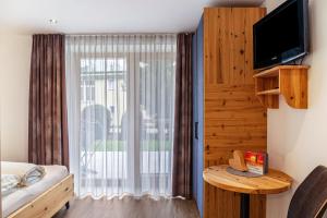um quarto com uma cama, uma televisão e uma janela em Apart-hochzillertal Gartenwohnung em Kaltenbach