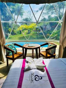 Cette chambre comprend un lit, une table et une fenêtre. dans l'établissement Shanti Wellness Sanctuary, à Lemery