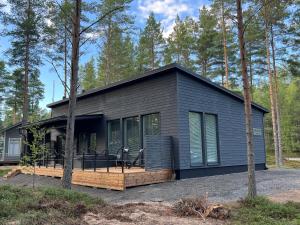 a black modular home with a deck and trees at Villa Dyyni Yyteri - Sauna & Hot Tub - Near Beach in Pori