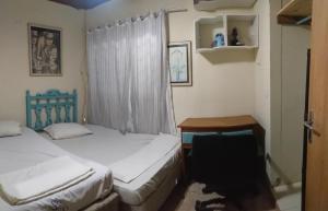 a bedroom with two beds and a desk and a window at MAZZAROTTO casa completa 2 quartos in Campo Grande