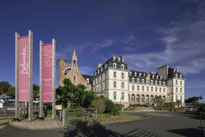 un gran edificio blanco con señales delante en Belambra Clubs Trégastel - Le Castel Sainte Anne, en Trégastel
