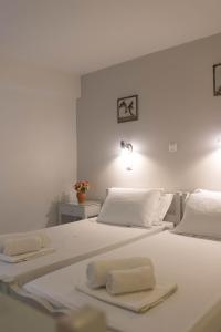 a white bedroom with two beds with towels on them at Studios Alsos in Naxos Chora
