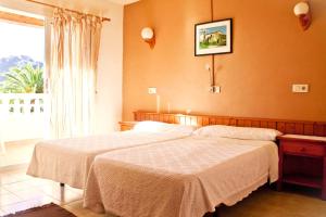 a bedroom with two beds and a large window at Fonda Las Palmeras in Font de Sa Cala
