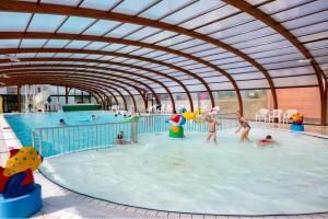 a group of people playing in an indoor swimming pool at Mobil-home 2023 RapidHome Panorama 3 chambres 6 vélos lave-vaisselle 2 piscines couvertes in Litteau