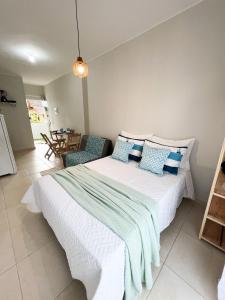 1 dormitorio con 1 cama blanca grande con almohadas azules en Villa 61 | Hospedagem, Praia de Armação, Beto Carrero - SC, en Penha