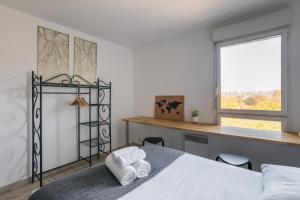 1 dormitorio con cama, escritorio y ventana en Le Cocon Voltaire - Appartement 2 chambres avec parking - Mabilais, en Rennes