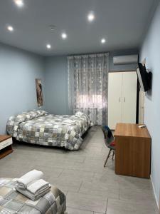 1 dormitorio con 2 camas, escritorio y TV en B&B Lolly, en Paravati