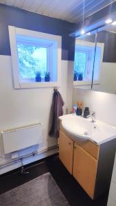 baño con lavabo blanco y 2 ventanas en Gårdshus en Lit