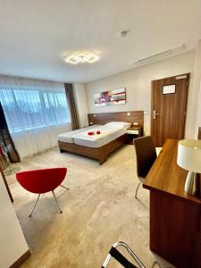 duża sypialnia z łóżkiem, biurkiem i krzesłami w obiekcie Pierre Hotel w mieście Pardubice