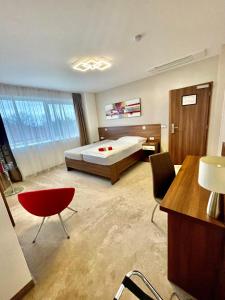 - une grande chambre avec un lit, un bureau et des chaises dans l'établissement Pierre Hotel, à Pardubice