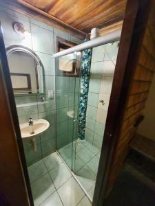 uma casa de banho com uma cabina de duche em vidro e um lavatório. em Pousada e Hostel Caminho de Santiago em Alto Paraíso de Goiás