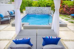 a swimming pool with two chairs and a table at Blessed Manor by Bluescape in Bridgetown