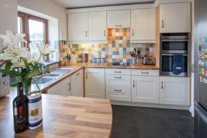 a kitchen with white cabinets and a table with flowers at Genesta in Saint Minver