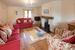 a living room with red couches and a fireplace at Genesta in Saint Minver