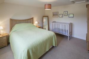 a bedroom with a green bed and a crib at Genesta in Saint Minver