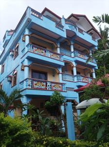 a blue building with balconies and trees at Ocean Breeze Inn in Boracay