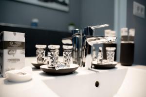 a bathroom counter with a sink with cups and a faucet at Luxury Down Town in Bucharest