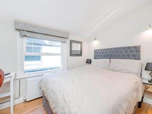 Un dormitorio blanco con una cama grande y una ventana en 4 Bedroom Residence Hammersmith Fulham, en Londres