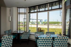 een eetkamer met een tafel, stoelen en ramen bij Hotel de Blaauwe Leeuw in Terneuzen