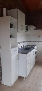 uma cozinha com armários brancos e um lavatório azul em Cabaña Las Brisas em Plottier