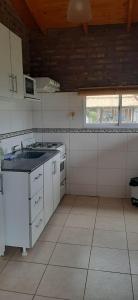 a white kitchen with a sink and a window at Cabaña Las Brisas in Plottier