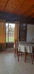 comedor con mesa, sillas y ventana en Cabaña Las Brisas en Plottier