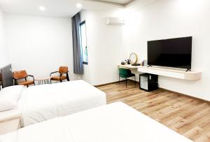 Una habitación de hotel con dos camas y un televisor de pantalla plana. en HERA HOSTEL, en Chau Doc