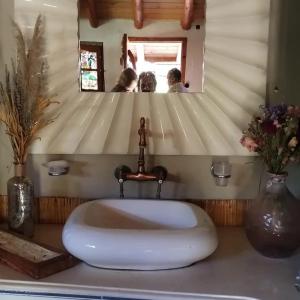 Cabañas La Oma Intiyaco في Atos Pampa: حمام مع حوض أبيض أمام مرآة
