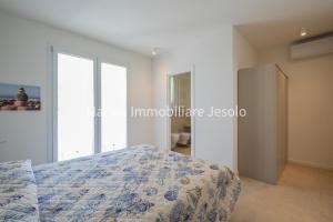 ein weißes Schlafzimmer mit einem Bett und einem Fenster in der Unterkunft PER MAR in Lido di Jesolo