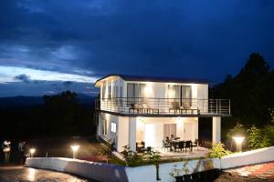 Casa blanca con balcón por la noche en RK MOUNT ORCHID coorg, en Madikeri